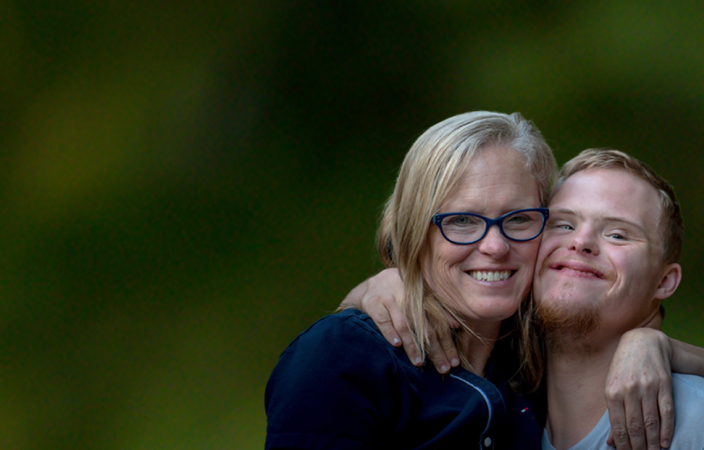 A boy with Down syndrome laughing and hugging his parents