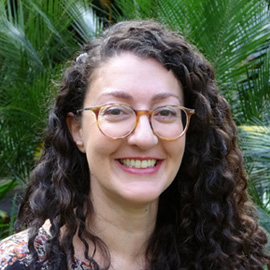 Makrina smiling to camera with deep green fern leaves in the background
