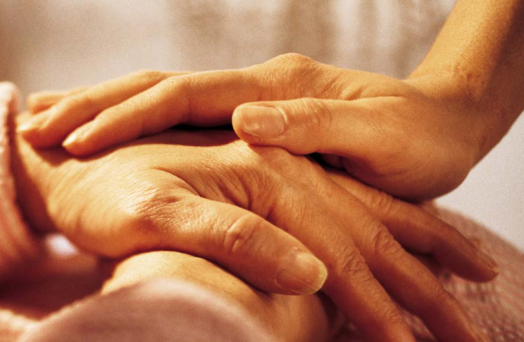 Two hands touch - a person comforts an older person