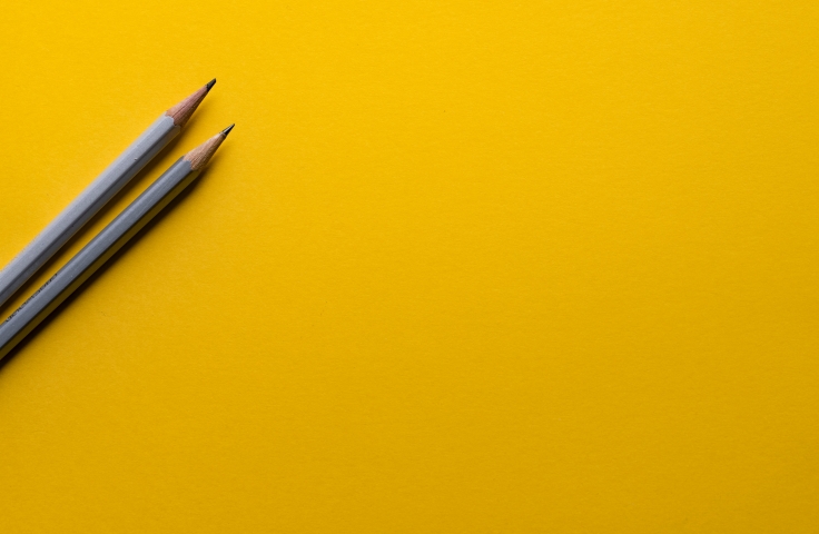 two pencils on a yellow table