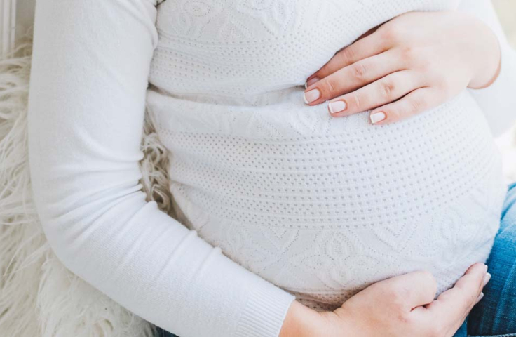 A pregnant woman cradles her belly